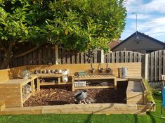 a wooden bench sitting on top of a lush green field next to a tree filled with potted plants