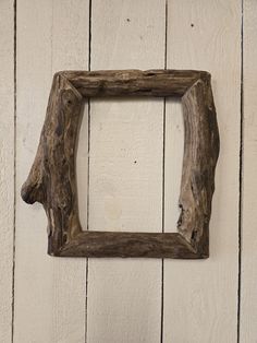 a frame made out of driftwood hanging on a white wall with wood planks