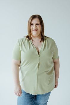 A person with shoulder-length brown hair wearing a light green KNIT BLOUSE WITH MANDARIN COLLAR by Love Marlow and jeans stands against a plain white background, smiling at the camera. Knit Blouse, Arm Sleeve, Mandarin Collar, Body Types, The Office, Round Neckline, Matcha, Comfort Fit, Let It Be