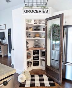 an open pantry door in the middle of a kitchen with white walls and wood floors