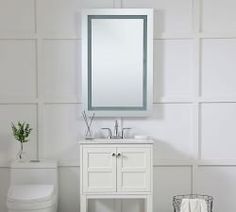 a bathroom with a toilet, sink and mirror on the wall next to it's tiled floor