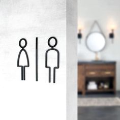 a bathroom with a sign on the wall that says man and woman in front of a mirror