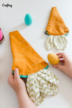 someone is holding an egg in front of some fabric gnome hats on a white table