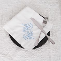 a plate with a fork, knife and napkin on it sitting on top of a bed