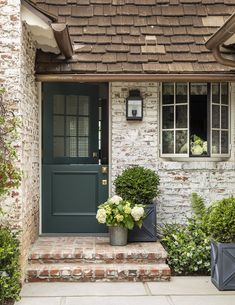 the front door of a brick house with two planters