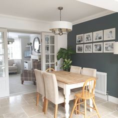 a dining room table with chairs and pictures on the wall behind it in an open living area