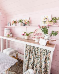 a room with pink walls and flowers on the shelf above the table, along with other decor items