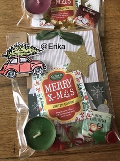 the contents of a christmas gift bag on a wooden table with candles and other items