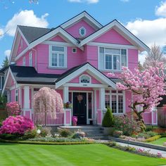 a pink house with white trim and lots of flowers in front of the entrance door