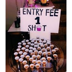 a table topped with lots of cups filled with liquid next to a sign that says entry fee 1 shot