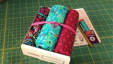 three rolls of fabric sitting on top of a cutting board