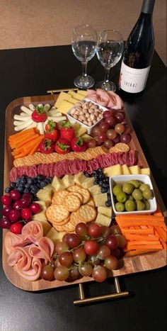 a wine bottle and two glasses on a table next to a platter of food