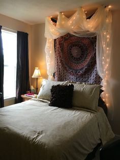 a bed with white sheets and lights on the headboard is in front of a window