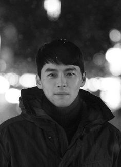 black and white photograph of a man standing in front of a street light at night