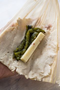 a sandwich wrapped in plastic with green peppers and cheese on the wrapper next to it