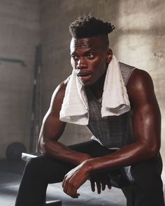 a man sitting on a bench with a towel around his neck and looking at the camera