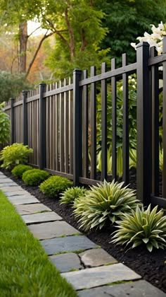 a black fence surrounded by green grass and flowers