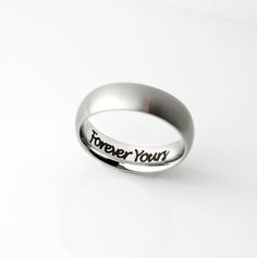 a silver ring with the words forever yours engraved on it's side, against a white background