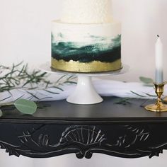 a white and green cake sitting on top of a table next to a lit candle