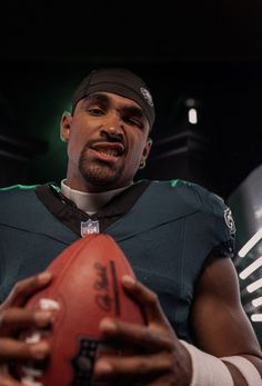 a close up of a football player holding a ball in his hands and looking at the camera