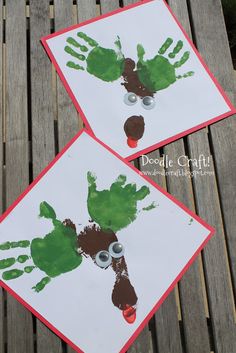 two handprints on white paper with green and red designs are sitting on a wooden bench