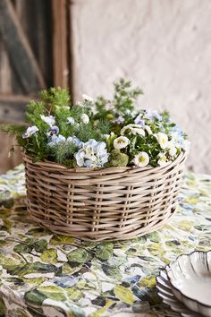 a basket filled with flowers sitting on top of a table next to a plate and fork