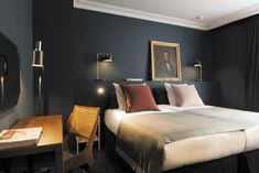 a hotel room with a bed, desk and chair in it that is dark blue