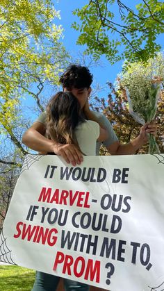 two people hugging each other while holding a sign that says it would be marvel - ous if you could swing with me to prom