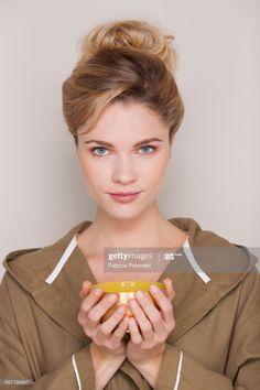 a young woman holding an orange in her hands, looking at the camera stock photo