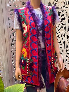 This vintage embroidered vest is so gorgeous! Perfect for concerts, festivals, or a night out! Embroidered silk. Fully lined, pockets and purple Mongolian fur trim. Best fits M to L. Winter Floral Embroidered Sleeveless Vest, Sleeveless Winter Vest For Festivals, Red Vest For Fall Festival, Bohemian Sleeveless Embroidered Outerwear, Sleeveless Festival Outerwear, Embroidered Sleeveless Outerwear For Winter, Bohemian Sleeveless Outerwear For Winter, Sleeveless Festival Vest With Pockets, Sleeveless Vest With Pockets For Festivals