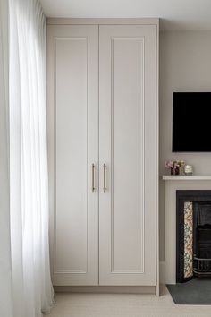 a living room with white furniture and a flat screen tv mounted on the wall above a fireplace