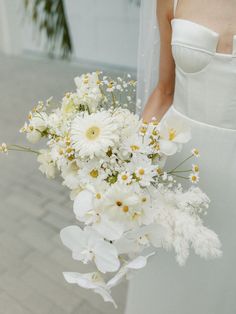 a bride holding a bouquet of white flowers