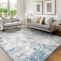 a living room with two couches and a rug on the floor in front of large windows