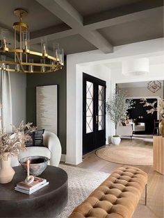 a living room filled with furniture and a chandelier hanging from the ceiling in front of a doorway