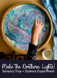 a child's hand on top of a bowl filled with blue and purple liquid