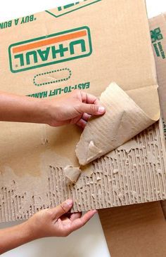 two hands are peeling cardboard from a box