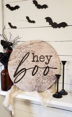 there is a sign that says hey boo on the shelf next to candles and bats