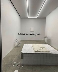 an empty room with a bed in the middle and words on the wall above it that read comme des garcos