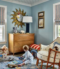 a young child playing with toys in a blue room, while sitting on the floor