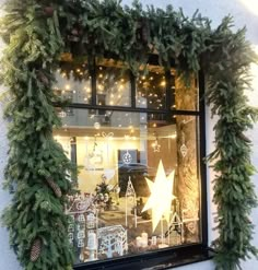 a store window decorated with christmas decorations and garlands on the windowsill is lit up