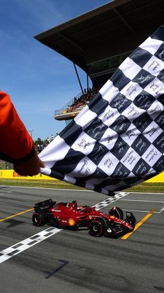 a person holding a checkered flag next to a race car