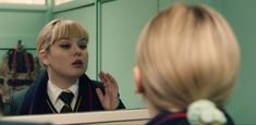 a woman in a school uniform is looking at herself in the mirror and talking to her friend