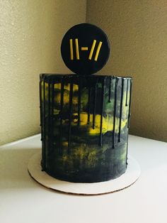 a black and yellow cake sitting on top of a white table next to a wall