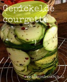 a jar filled with sliced cucumbers sitting on top of a metal wire rack