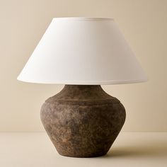 a brown vase with a white lamp on it sitting on a table next to a wall