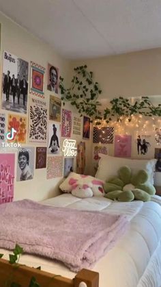 a bed with lots of pictures on the wall above it and plants growing in the corner