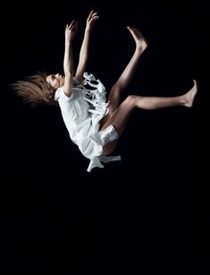 a woman flying through the air while wearing a white dress