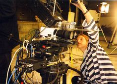 a woman sitting in front of a camera on top of a tripod with her hand up