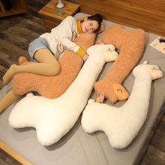 a woman laying on top of a bed with two stuffed animals in the shape of giraffes