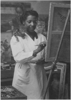 an old black and white photo of a woman holding a cat in front of a easel